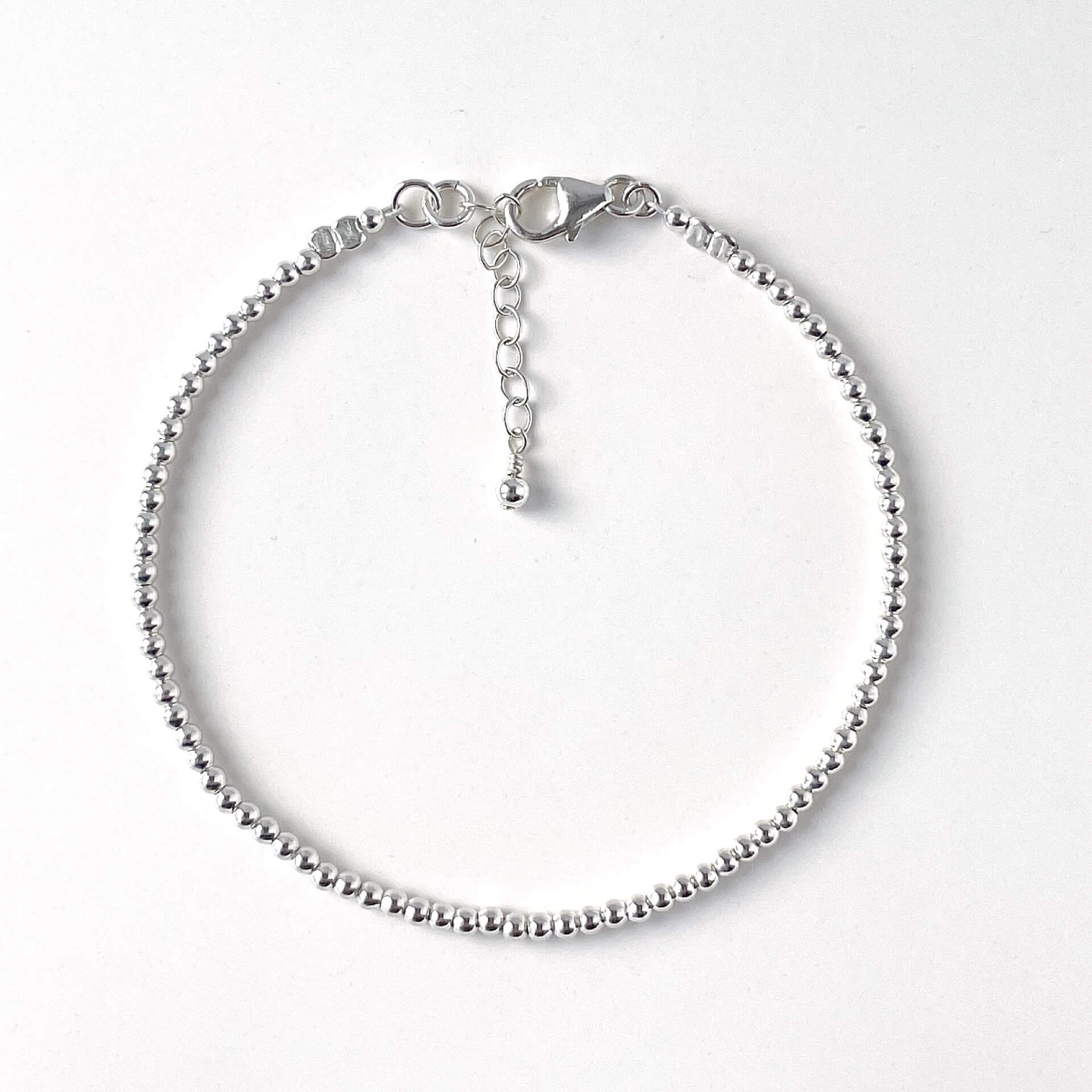 Minimalist sterling silver bead bracelet with 2mm beads on a white background