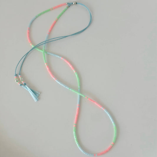 Dainty green, pink and pale blue glass bead necklace with sterling silver sliding clasp on a white flat lay surface
